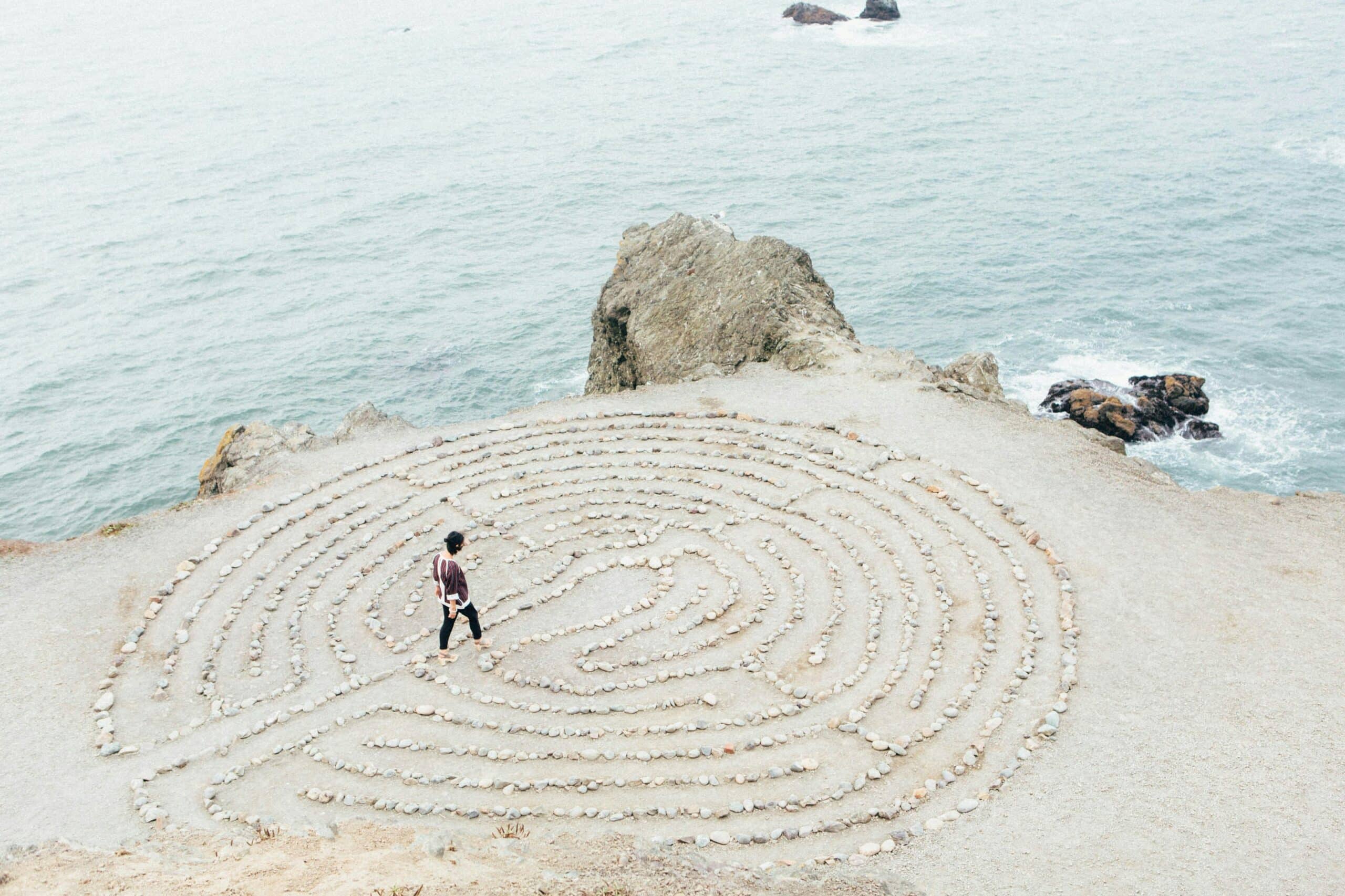 someone walking through a prayer labyrinth in the sand overlooking the ocean