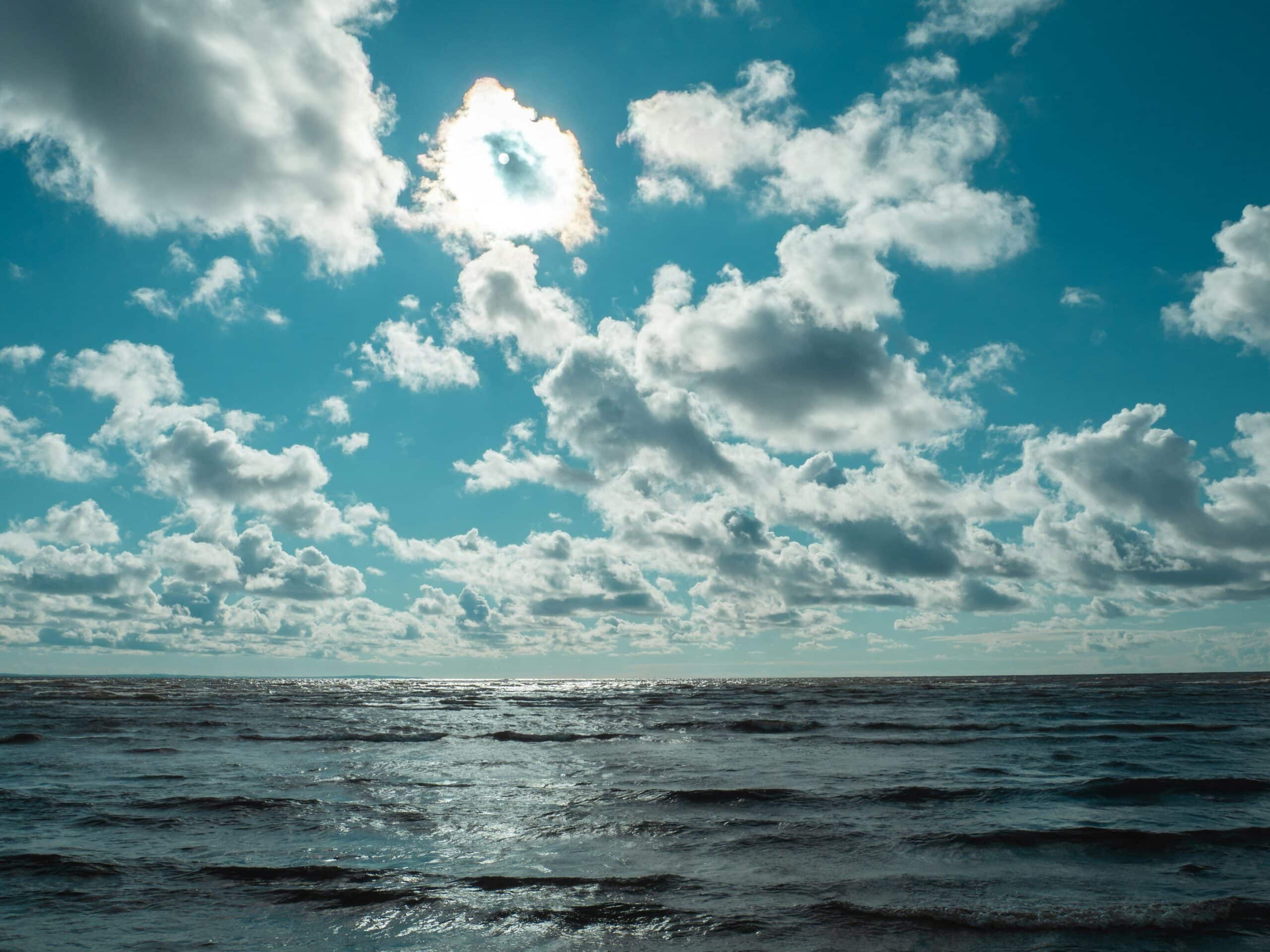 sunny day with clouds overlooking a still ocean